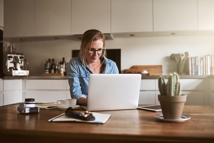 A woman sitting at a table explores how to send large files on her laptop.