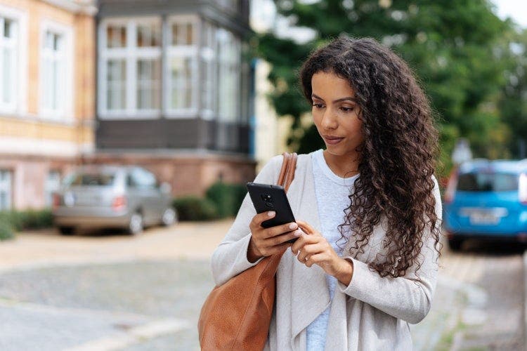 A woman standing outside uses an Android phone to add password protection to a PDF file.