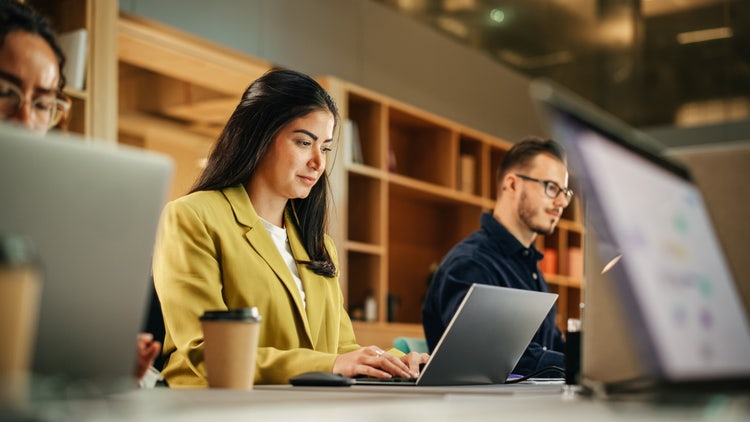 A woman uses a laptop to customize a grant proposal template.