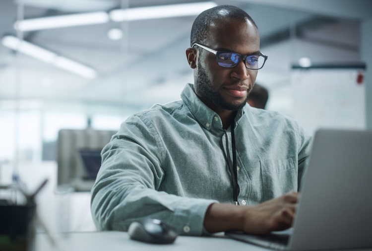A man types on a laptop to add a signature line in Word on a Mac.