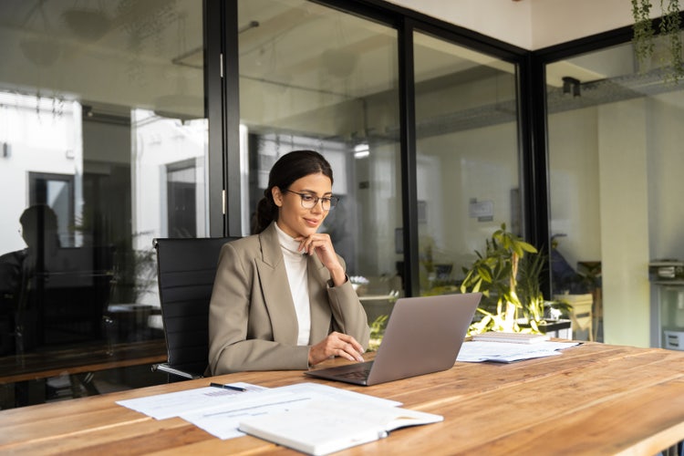 A person sitting at a table and using a laptop computer to make a fillable PDF form.