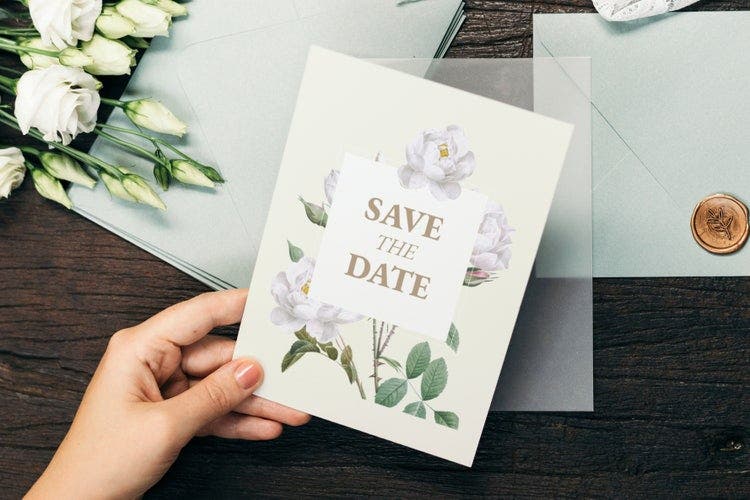 A woman holds a save-the-date flyer made from a template in Adobe Acrobat.
