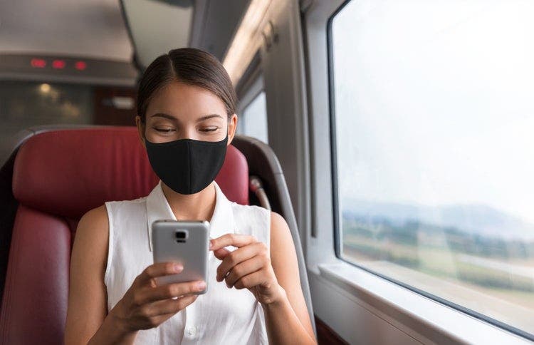 A woman wearing a face mask combines PDF files using an Android device while commuting.