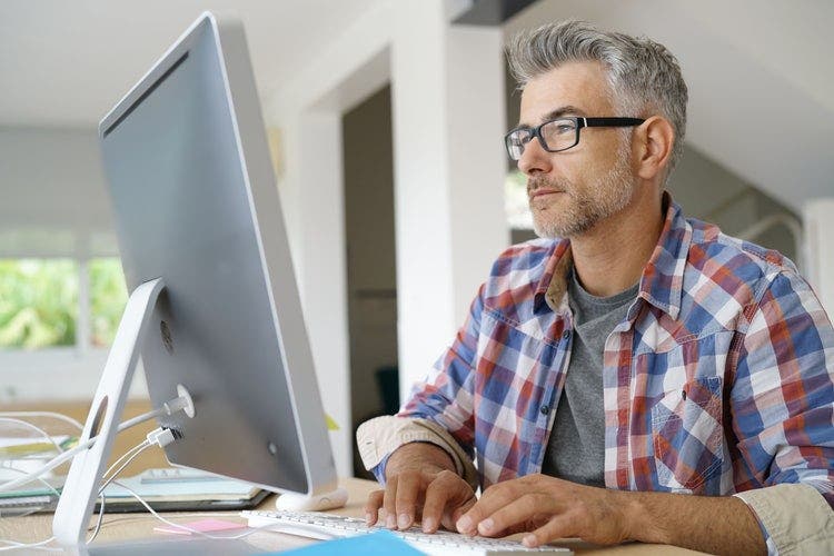 A man uses a desktop to copy and paste a PDF into Word document.