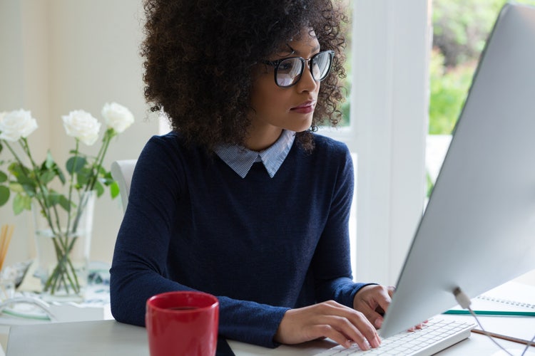 A photo of a person sitting at a desk and working on a computer.