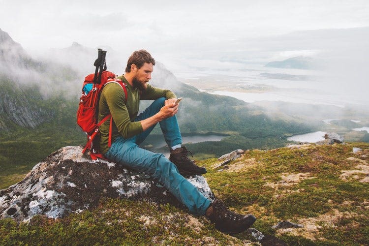 A person edits a PDF using an Android device atop a mountain.