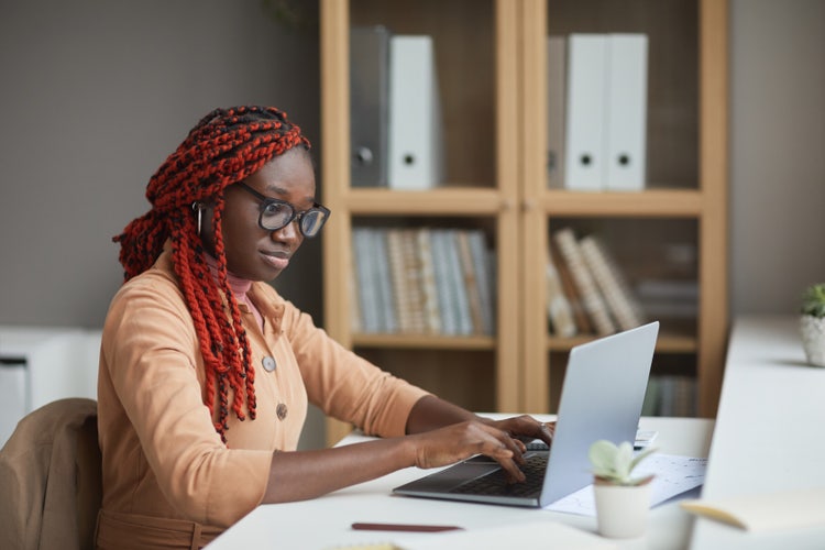A woman uses a laptop computer to complete a travel consent form for a minor.