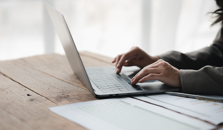 A person sitting at a table types on a laptop.