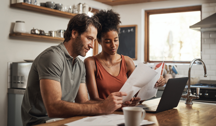 A couple sitting on a couch reviewing a paper mortgage note together