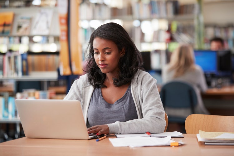 A student on her laptop learns how to structure a college essay while in the library.