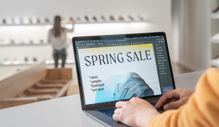 A person sitting in a shoe store works on a document on their laptop.