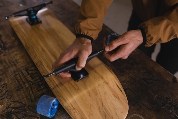A skateboard shop worker installing wheels onto a skateboard truck in the workshop