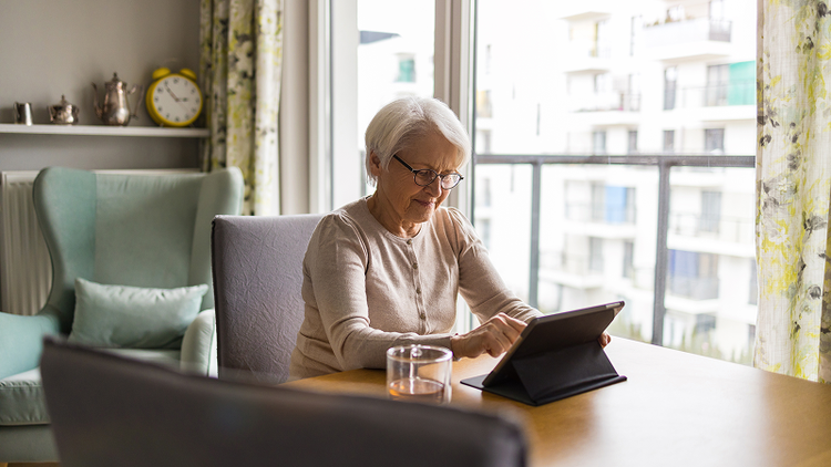 A homeowner reviewing a mortgage note on their tablet while sitting on a couch.