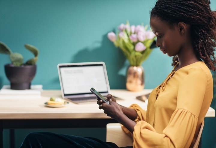A worker leaning sideways in their chair and looking at their phone to check a JPG that has been converted from a PDF