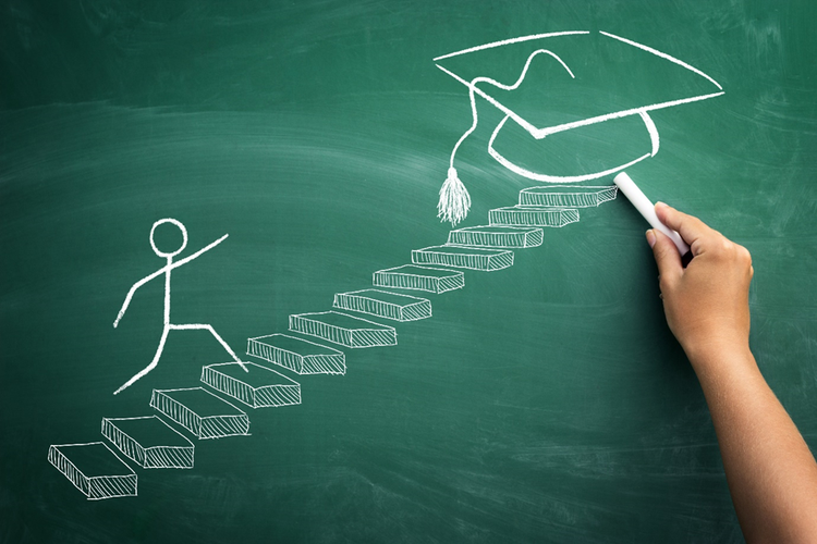 Photo of a person's hand drawing a stick figure on a chalkboard walking up steps to a graduation cap at the top.