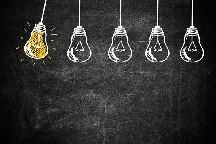 Series of five light bulbs suspended over a chalkboard. One is coloured bright yellow, indicating it is lit up.