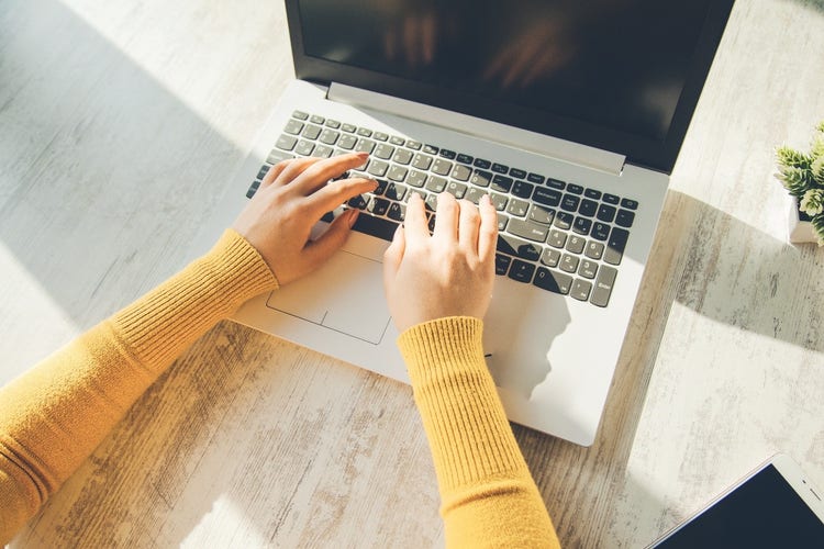 Woman typing on laptop keyboard.