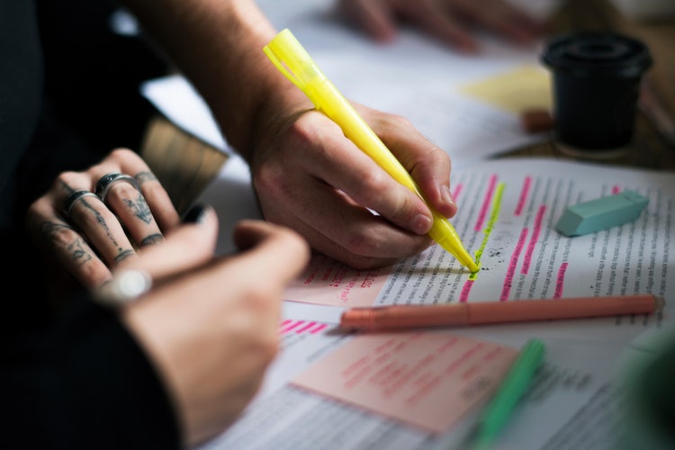 Person highlighting printed text on paper with a pen