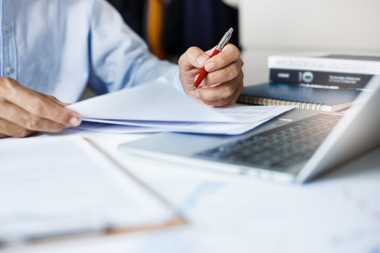 A man is holding a pen to sign documents with a wet signature.
