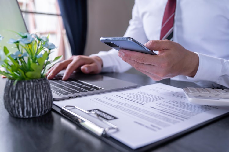 Businessman looking at a computer and printed form