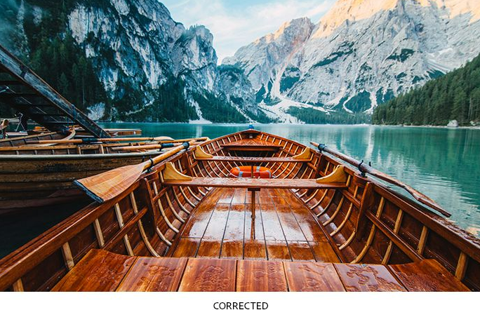 A raw vs. corrected photo of a wooden boat on a mountain lake