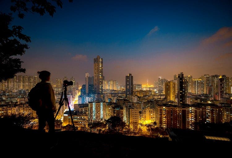 A photographer capturing a night-time shot of a city skyline