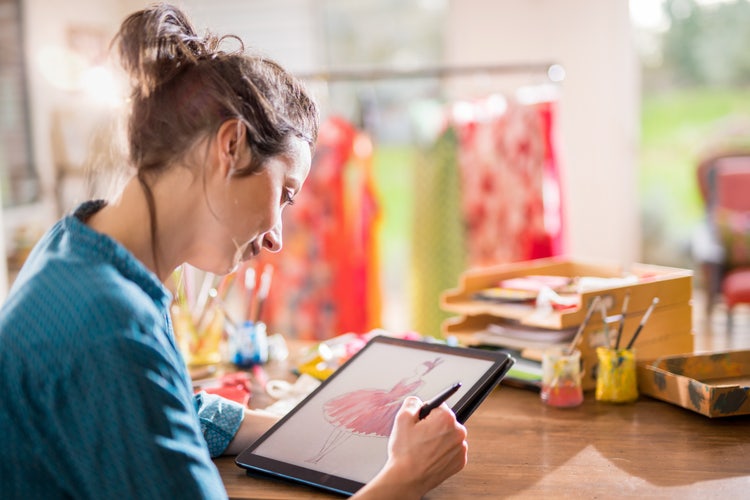 Fashion designer sketching a new clothing design on a digital tablet.