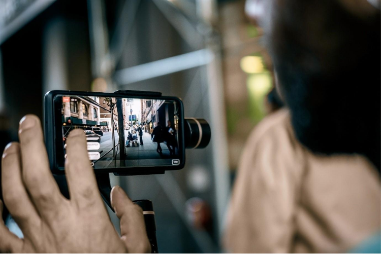 Man using phone with stabilizer and taking pictures and video in New York city for a faceless vlog.