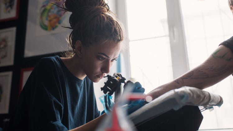 Tatoueuse réalisant un nouveau tatouage sur le bras d’une cliente