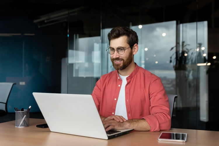 Homem sentado em frente a um laptop explorando dicas de design para PowerPoint.