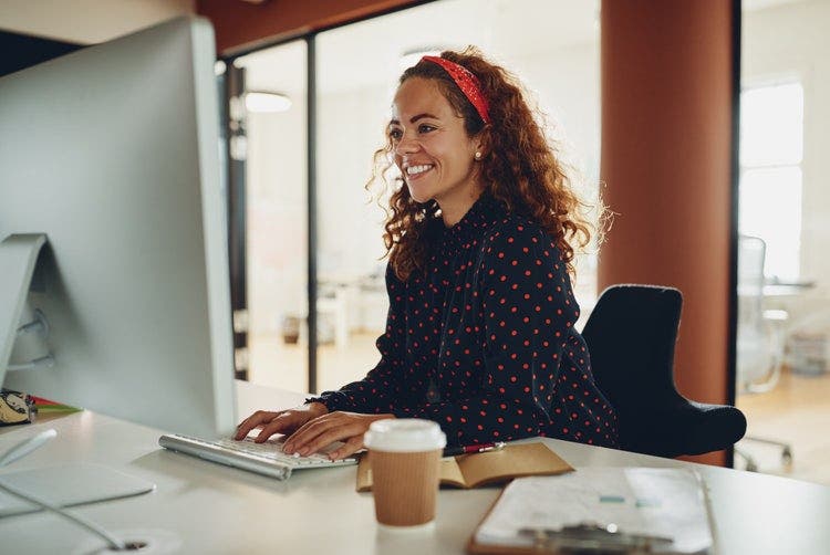 Uma mulher em um escritório usa um computador desktop para converter um PDF em PDF/A.