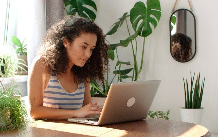Uma mulher sentada à mesa usando um notebook para remover realces de arquivos PDF.