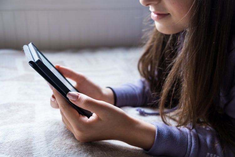 Uma mulher segurando um Kindle adiciona um PDF ao dispositivo.