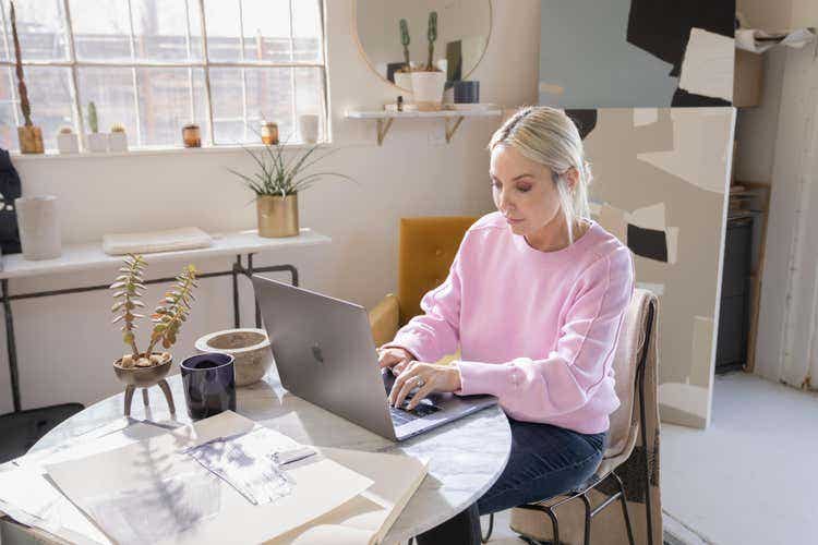 Uma pessoa está sentada a uma mesa pequena usando um notebook para converter arquivos AI em PDFs.