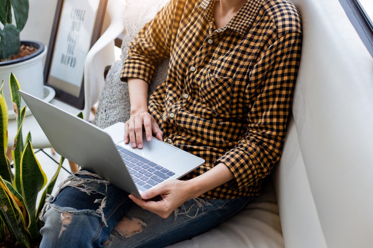 Pessoa sentada no sofá cria uma carta de apresentação em PDF usando um notebook.