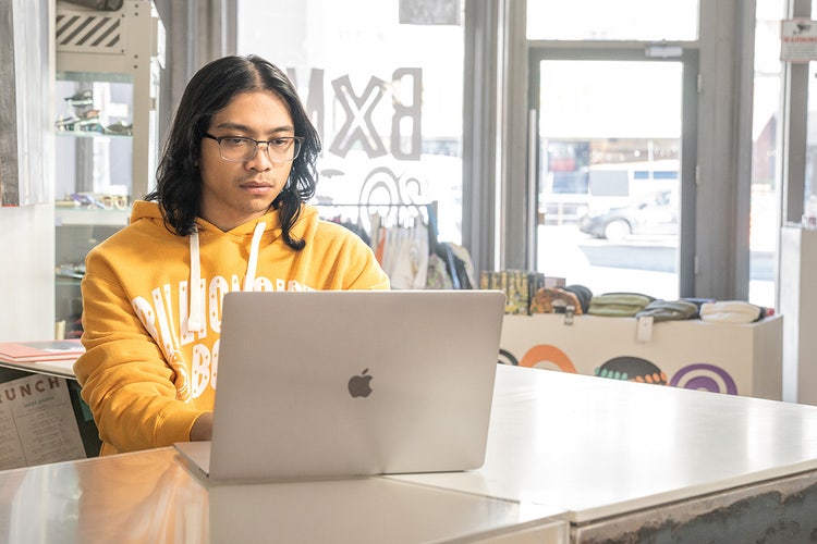 Pessoa de moletom amarelo adicionando um índice a um PDF usando um notebook Mac sobre uma mesa branca.