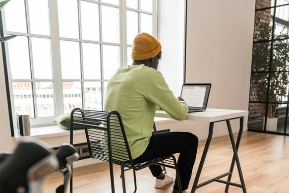 Uma foto de uma pessoa sentada em uma mesa de escritório digitando uma declaração de tese em um laptop.
