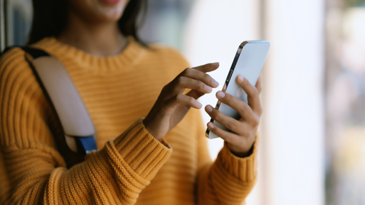 Woman with phone A woman wearing a yellow jumper looks at her mobile phone.