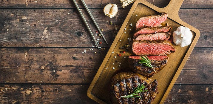Savory food photo of a garlic and rosemary grilled steak on a cutting board
