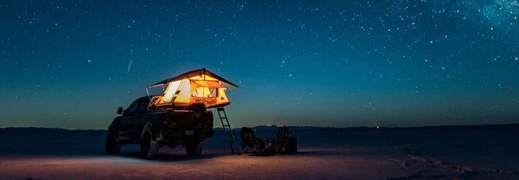 A pickup truck and tent under a starry sky at night, Picture