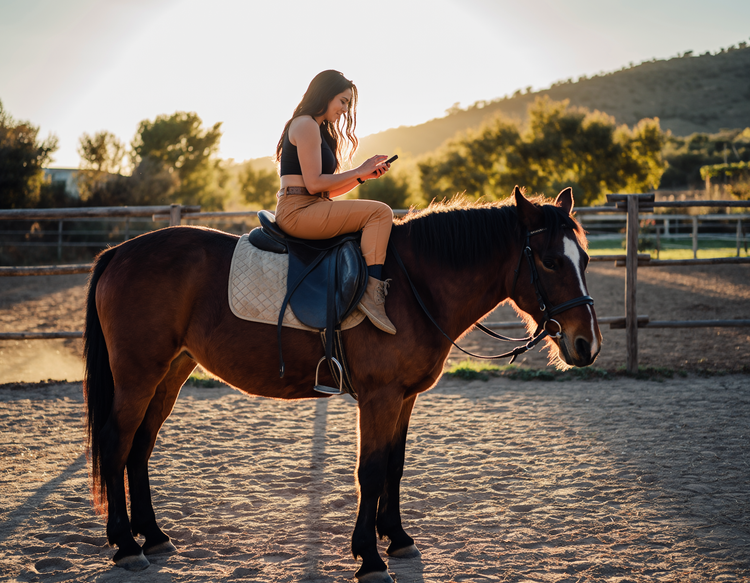 Femme à cheval, de profil, générant un effet sonore avec l’application mobile Firefly sur son smartphone
