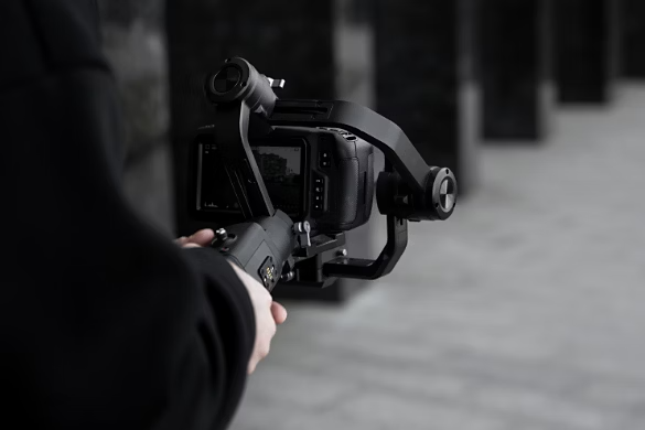 A camera operator shooting video in a stark setting on a DSLR using a handheld gimbal to stabilize their shot