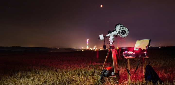Ночная съемка астрономических фотографий в поле с помощью телескопа.