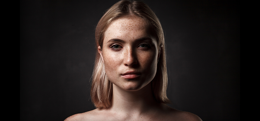 Portrait de femme avec des taches de rousseur sur fond noir