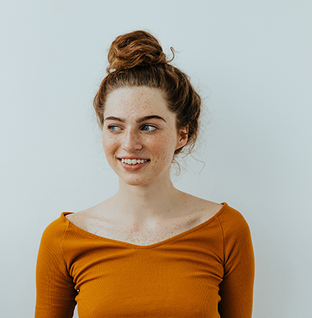 Portretfoto van een vrouw met roodbruin haar en een oranje shirt 