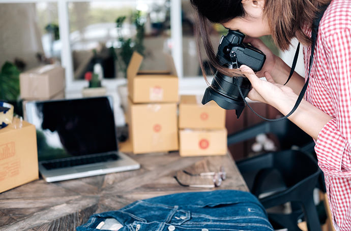 Woman in a red-checkered shirt taking a still-life picture of denim shirt
