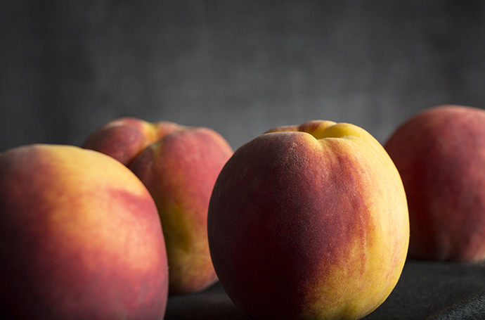 Still life photo of an assortment of fresh peaches on a dark background
