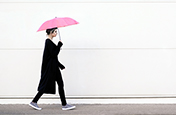 Uso da regra dos terços para fotografar uma mulher caminhando com um guarda-chuva rosa