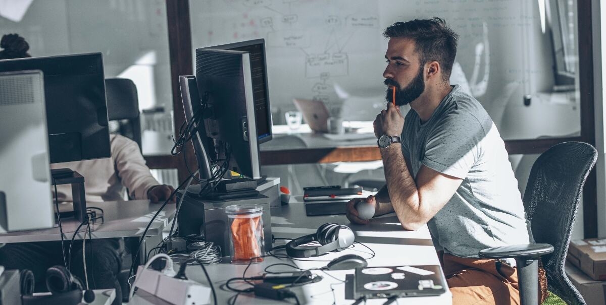 Joven programador sentado en la mesa de su despacho y trabajando.