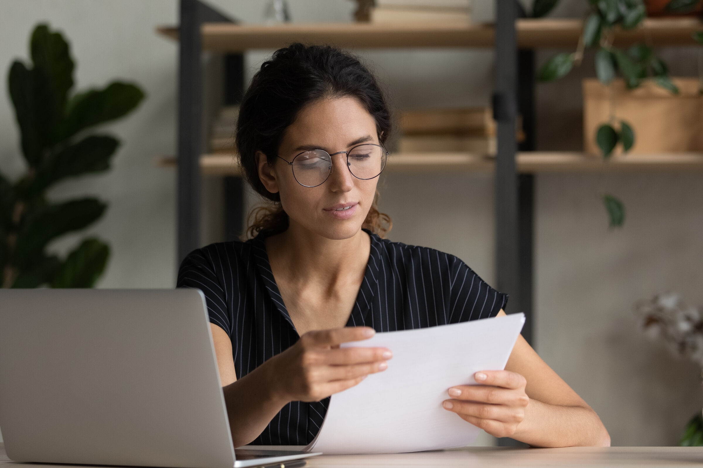 une collaboratrice lit une lettre dans son bureau